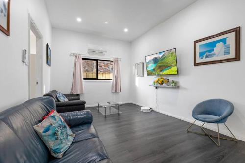 a living room with a leather couch and a chair at Spacious Wyong Getaway in Wyong