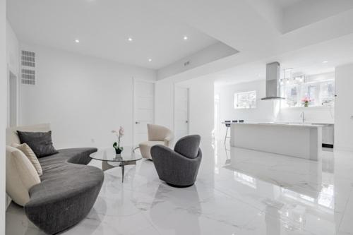 a white living room with two chairs and a table at Comfortable Room in Toronto next to Yorkdale mall in Toronto