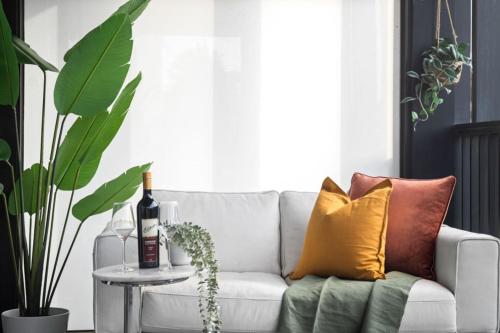 a white couch with colorful pillows and a bottle of wine at Sunny Richmond Escape 2BR and Large Balcony in Melbourne