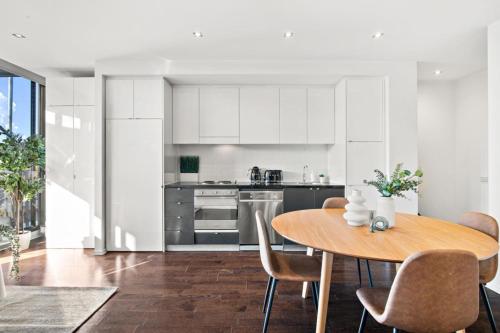 a kitchen with a wooden table and chairs in a room at Sunny Richmond Escape 2BR and Large Balcony in Melbourne