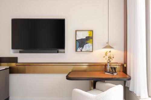 a room with a table and a tv on a wall at Kimpton Naluria Kuala Lumpur by IHG in Kuala Lumpur