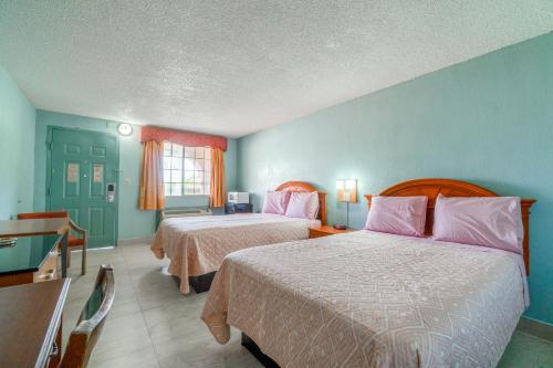 a hotel room with two beds and a window at Lone Star Inn & Suites by OYO Harlingen TX in Harlingen