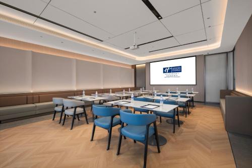 a conference room with tables and chairs and a screen at Holiday Inn Express Qingdao City Balcony by IHG in Qingdao