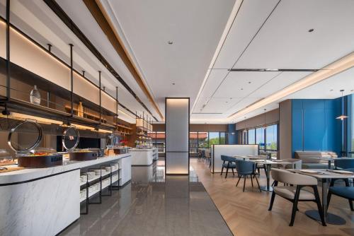 an open kitchen and dining room with tables and chairs at Holiday Inn Express Qingdao City Balcony by IHG in Qingdao