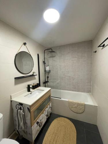 une salle de bain avec un lavabo, une baignoire et un miroir dans l'établissement Appartement Aldapa, à Urrugne