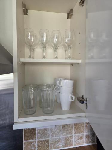 a shelf with wine glasses and cups on it at Spacious - 8ight Havens Folkestone in Folkestone