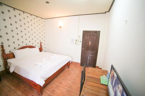a bedroom with a bed and a flat screen tv at Maylay Guesthouse in Vang Vieng