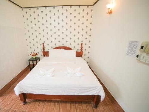 a bedroom with a bed with white sheets and butterfly pillows at Maylay Guesthouse in Vang Vieng