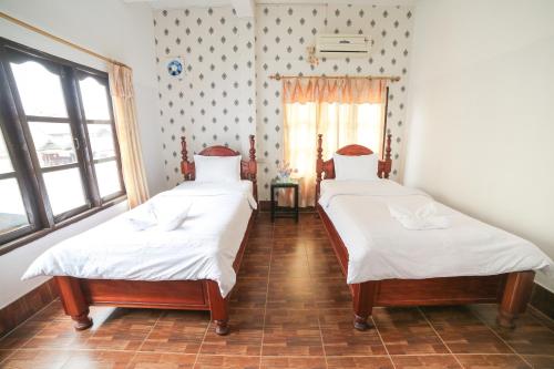 two twin beds in a room with a window at Maylay Guesthouse in Vang Vieng