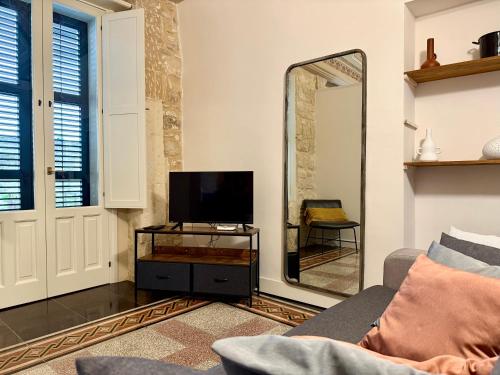 a living room with a tv and a mirror at Casa San Pietro - Scicli in Scicli