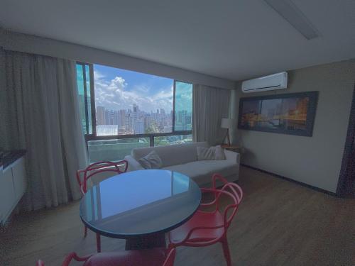 a living room with a couch and a table and chairs at Flat Exclusivo com Cozinha Completa, Piscina e Próximo à Praia Boa Viagem in Recife