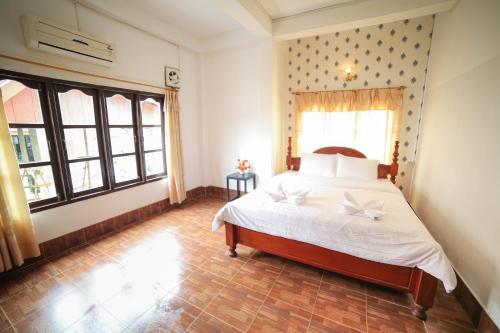 a bedroom with a bed with white sheets and a window at Maylay Guesthouse in Vang Vieng