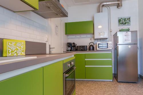 - une cuisine avec des placards verts et un réfrigérateur dans l'établissement La Villa Pop, à Joué-lès-Tours