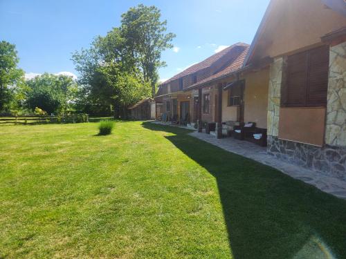 a yard next to a building with a grass field at Dvor in Donja Toponica