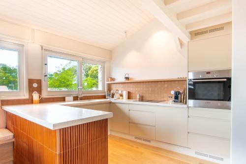 une cuisine avec des armoires blanches et un comptoir dans l'établissement Atlantic Selection - Le Pasteur, au lac d'Hossegor, à Soorts-Hossegor