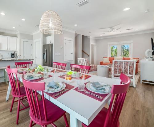 a kitchen and dining room with a white table and red chairs at Salty Shells by The Madison Liv Collection in Orange Beach