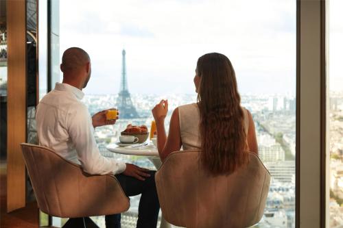 a man and woman sitting at a table with a plate of food at Hyatt Regency Paris Etoile in Paris