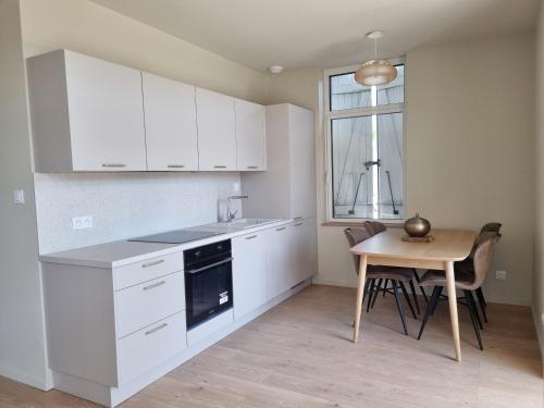 une cuisine avec des armoires blanches, une table et une fenêtre dans l'établissement Le Terrazzo - Jardin & confort, à Meximieux