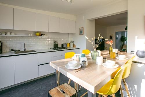 une cuisine avec une table en bois et des chaises jaunes dans l'établissement Maison Jardin - Centre Angers, à Angers