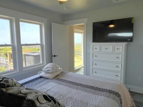 a bedroom with a bed and a dresser and windows at Fishin' Shack in Oak Island