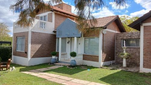 una casa in mattoni con una porta bianca di CASA TODA EN PLANTA BAJA CON PARQUE y PILETA INDIVIDUAL SOBRE ASFALTO A POCAS CUADRAS DEL CENTRO DE MERLO a Merlo