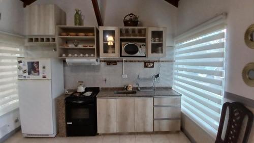 una piccola cucina con fornelli e frigorifero di CASA TODA EN PLANTA BAJA CON PARQUE y PILETA INDIVIDUAL SOBRE ASFALTO A POCAS CUADRAS DEL CENTRO DE MERLO a Merlo