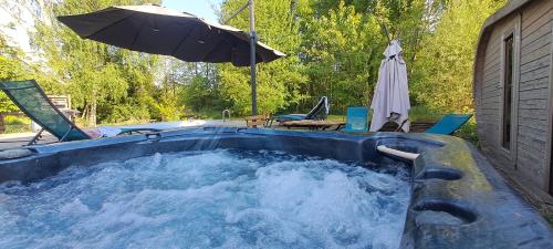 a hot tub with an umbrella and a table and chairs at Gîte de La Forge in Hesse