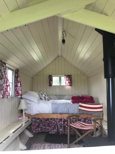 a bedroom with a bed and two chairs in a room at The Shepherds Hut in Hindringham