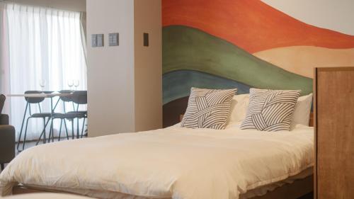 a bedroom with a bed with a large painting on the wall at Jomo Stay Takasaki in Takasaki
