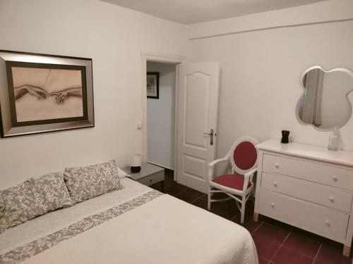マラガにあるFantástico apartamento con piscina comunitaria junto al mar en Málagaのベッドルーム1室(ベッド1台、ドレッサー、椅子付)