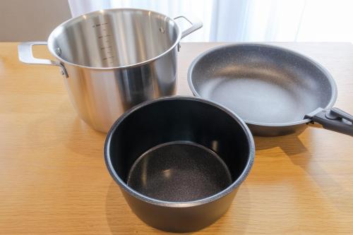 two pans sitting on a table next to a pot at Jomo Stay Takasaki in Takasaki