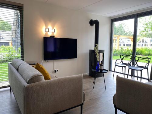 a living room with a couch and a flat screen tv at Chalet in Lochem near Forest & Cycling in Lochem