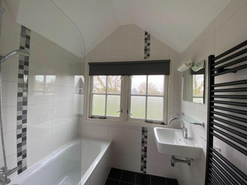 a white bathroom with a tub and a sink at Modern Dutch Villa with Terrace in Hippolytushoef