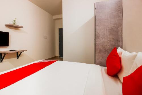 a bedroom with a bed with red and white pillows at Hotel O D' Jade in Hyderabad