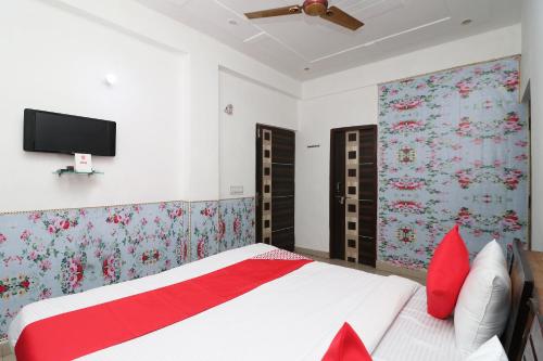 a bedroom with a bed with red pillows and a tv on the wall at Four Seasons in Sikandra