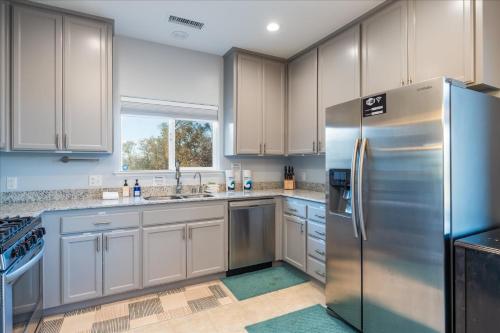 a kitchen with white cabinets and a stainless steel refrigerator at Hilltop Paradise with stunning views/hot tub/firepit/dog friendly in Oakhurst