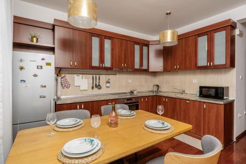 a kitchen with a wooden table with chairs and a refrigerator at Adriatic Lux Apartment in Bar
