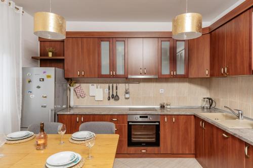 a kitchen with wooden cabinets and a table with chairs at Adriatic Lux Apartment in Bar