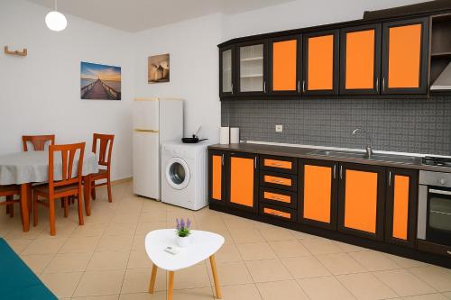 una cucina con mobili arancioni e un tavolo e una sala da pranzo di AURA apartaments29 a Durrës