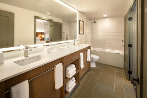 a bathroom with a sink and a toilet and a mirror at Hotel Terra Jackson Hole, a Noble House Resort in Teton Village