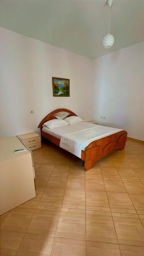 ein Schlafzimmer mit einem großen Bett und einem Holzboden in der Unterkunft Luani's Apartments in Vlorë
