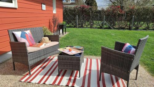 d'une terrasse avec 2 chaises en osier et une table. dans l'établissement Maison tout confort, à Saint-Romain-de-Colbosc