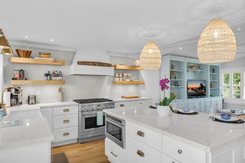 a white kitchen with white cabinets and a stove at Key Haven Coastal Retreat - Canal Front With Pool in Stock Island