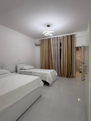 a white room with two beds and a window at ELIO's Room in Durrës