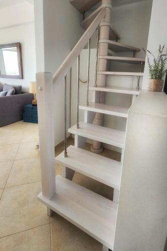 a white spiral staircase in a living room at Wave Whisper Home in Vathí