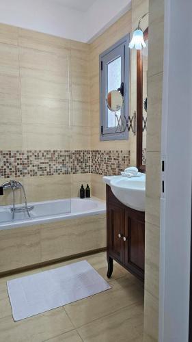 a large bathroom with a tub and a sink at Wave Whisper Home in Vathí