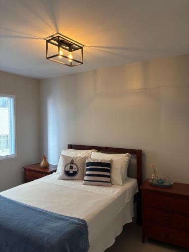 Apartamento Alto Padrão في غوارويا: غرفة نوم بسرير كبير واضاءة