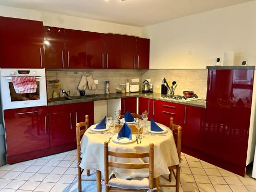 une cuisine avec des placards rouges et une table avec des chaises dans l'établissement Charming furnished house at Moret sur Loing, à Moret-sur-Loing