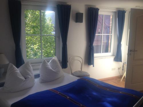 a bedroom with a bed with blue curtains and a window at Pension Kunsthof Dahrenstedt in Dahrenstedt