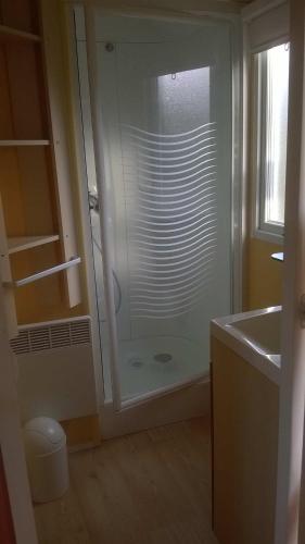 La salle de bains est pourvue d'une douche en verre, d'un lavabo et d'un comptoir. dans l'établissement Mobile home 12 lac de bairon, à Sauville